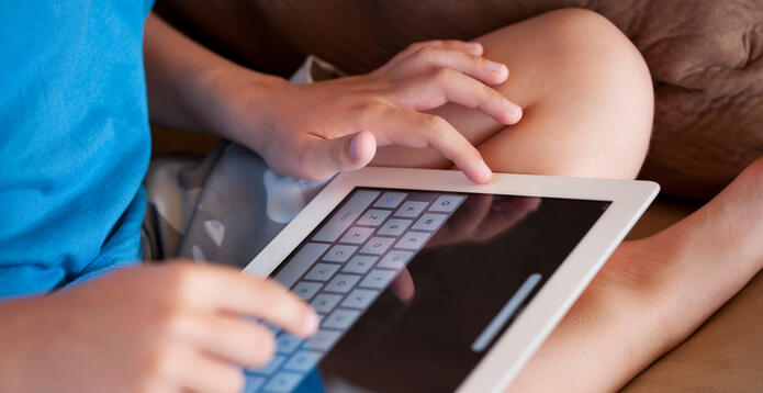 A child using the touch sensitive keyboard to write on an Apple iPad.