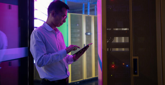 Engineer uses tablet to inspect data centre equipment