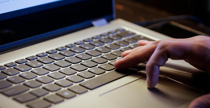 Young man uses laptop to electronically pay bills with his credit card