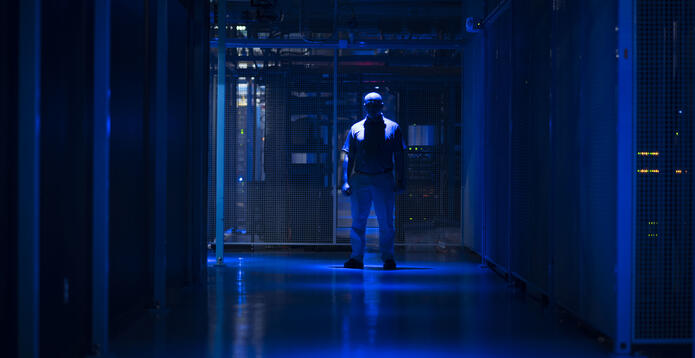Silhouetted man inside a data centre