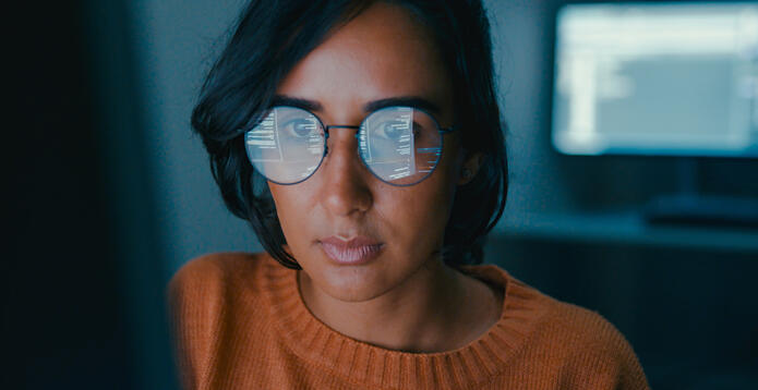 Women facing screen with info reflected in her glasses