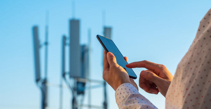 5G communications tower with man using mobile phone