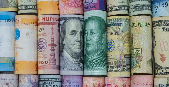 Rolled banknotes from around the world, including US dollars and Chinese yuan