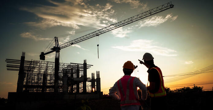 Silhouette of  a crane and workmen at a building site