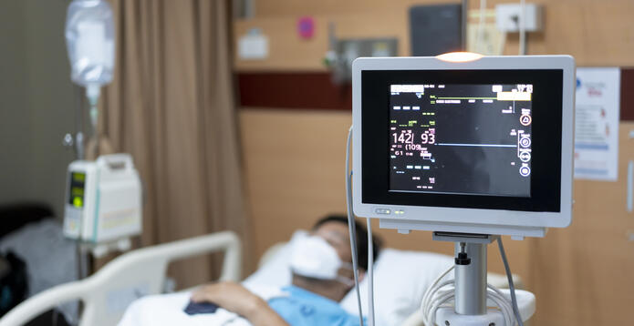 Hospital patient lying in bed with a vital signs monitor in the foreground