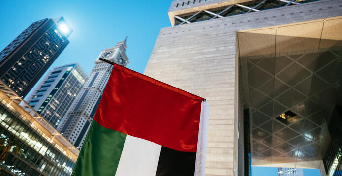 The Dubai International Financial Centre arch, with skyscrapers and the UAE flag