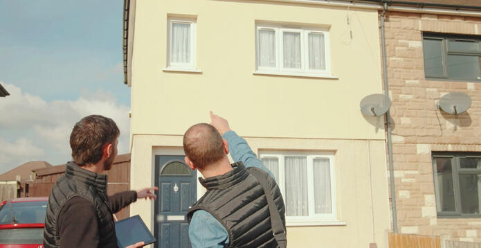 Two young men pointing at a council house