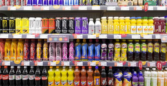Rows of bottles of colourful fizzy drinks on display in a supermarket