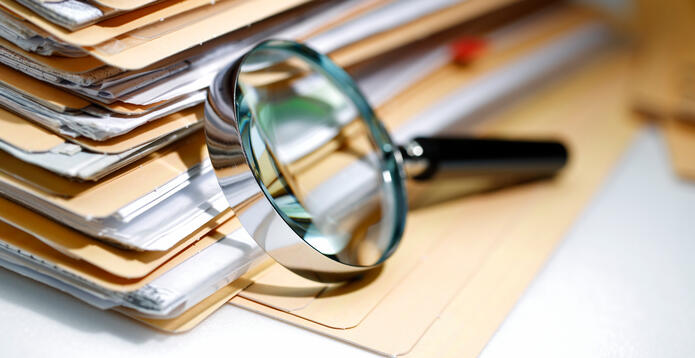 Documents pile and magnifying glass