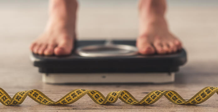 Bare feet on a bathroom scale with a measuring tape in front