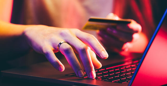 A woman holding a credit card and using a laptop while online shopping