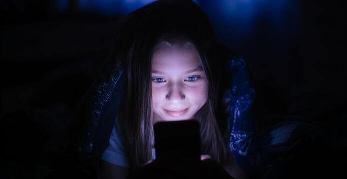Girl with face illuminated by smartphone