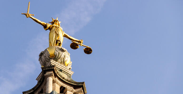 Statue of Lady Justice holding scales and a sword against a blue sky