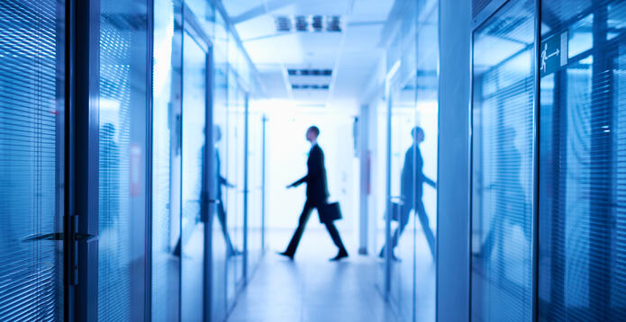 Silhouette of businessman with portfolio walking in background, dark long corridor of spy organization.