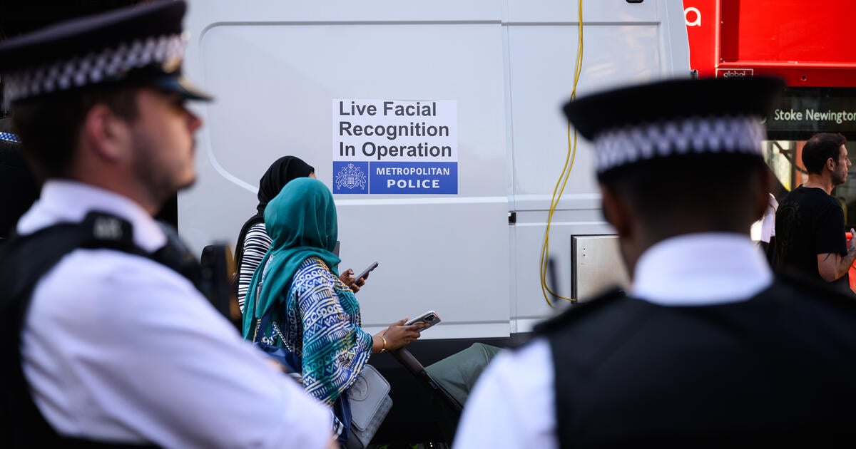 Metropolitan Police officers next to a van, displaying a sign warning that live facial recognition is in operation