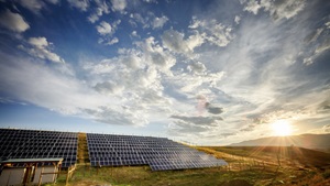 Solar Panels and Green Field Under Dramatic Sky at Sunset