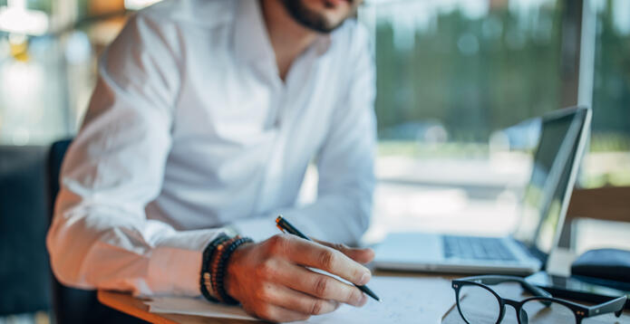 Businessman signing contract in cafe by a laptop