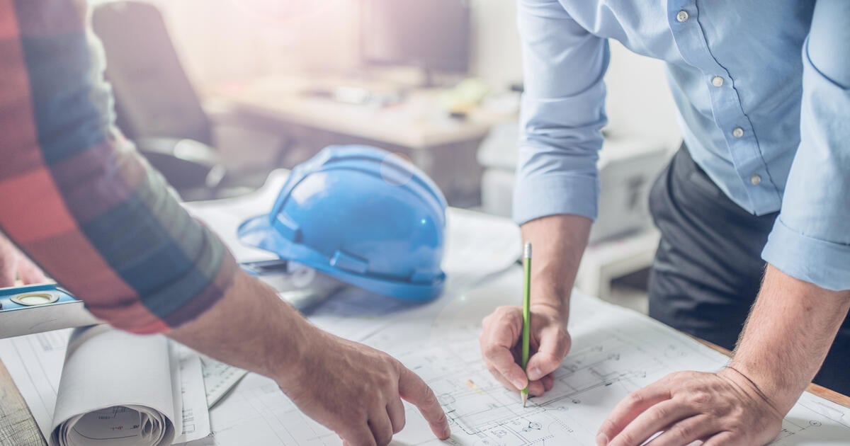 Hands of an architect and an engineer pointing at the architectural plan