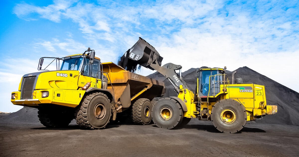 Yellow dump truck being loaded by a large excavator at a quarry site