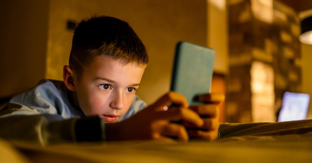 Boy holding mobile on side of bed