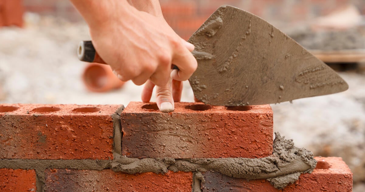 Bricklayer hands on red brick