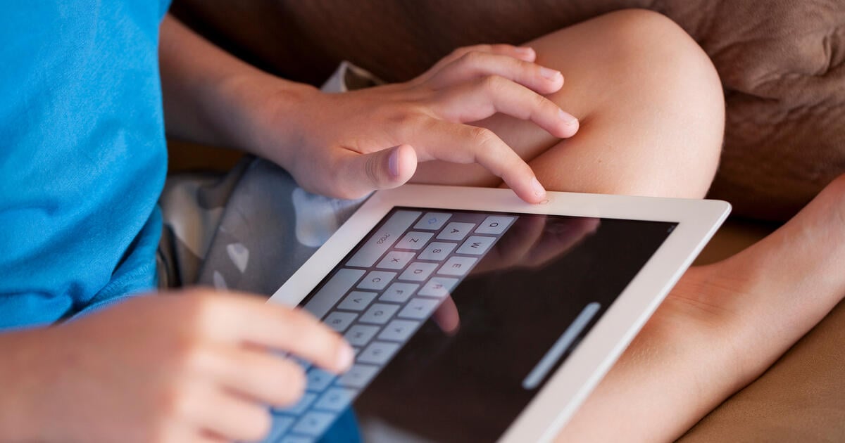 A child using the touch sensitive keyboard to write on an Apple iPad.