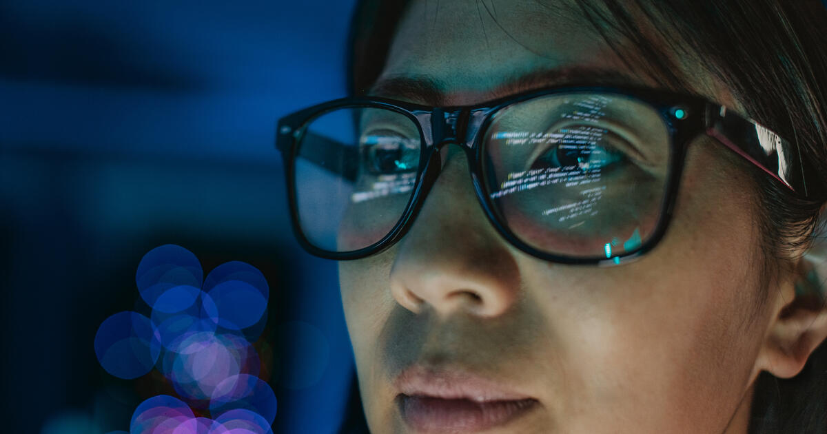 Glasses on woman reflect data on screen