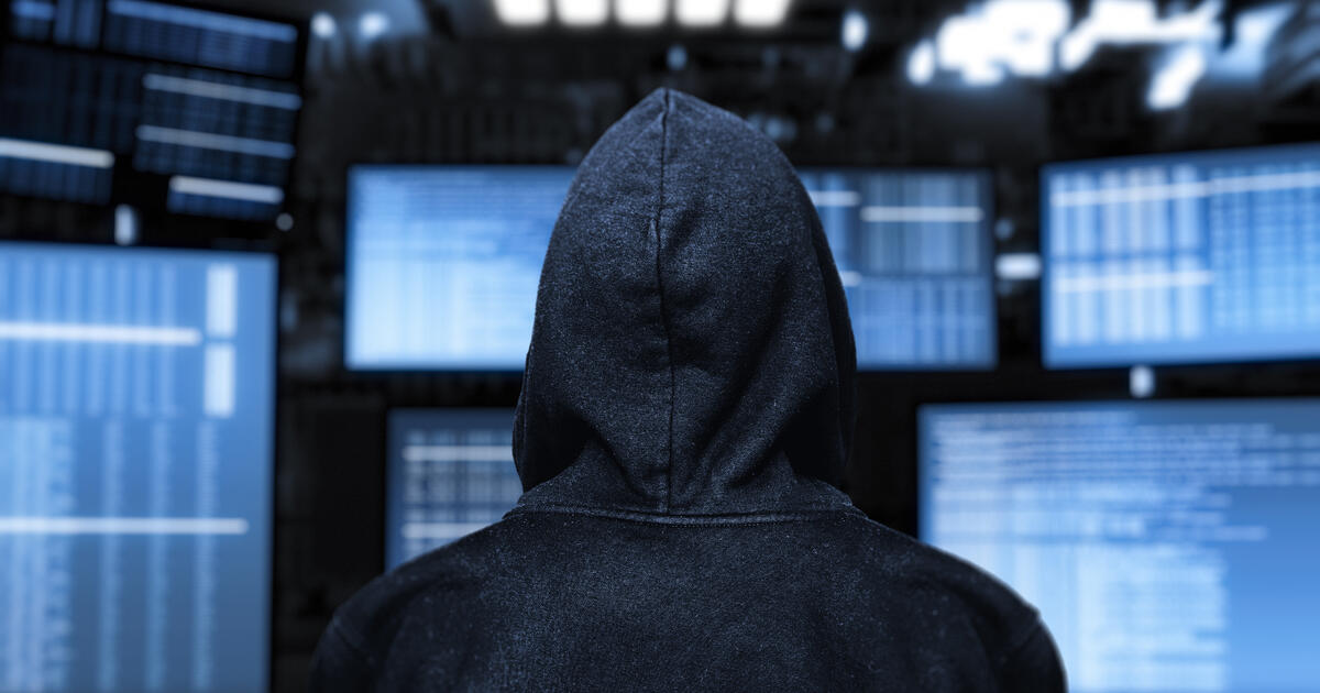 Hooded hacker facing screens