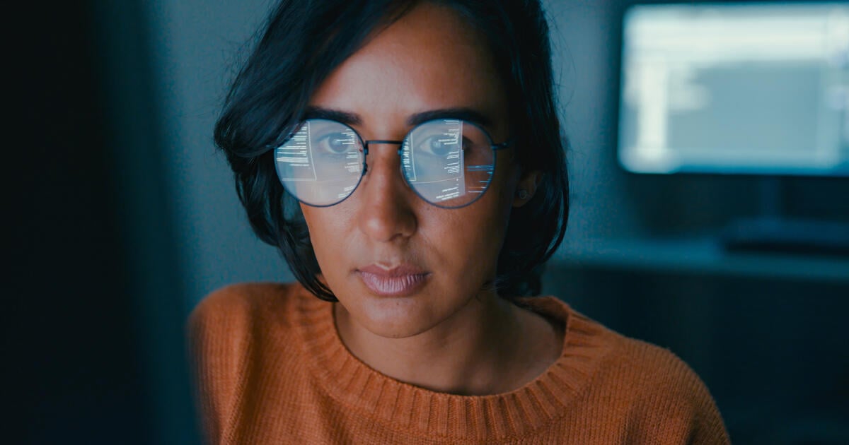 Women facing screen with info reflected in her glasses