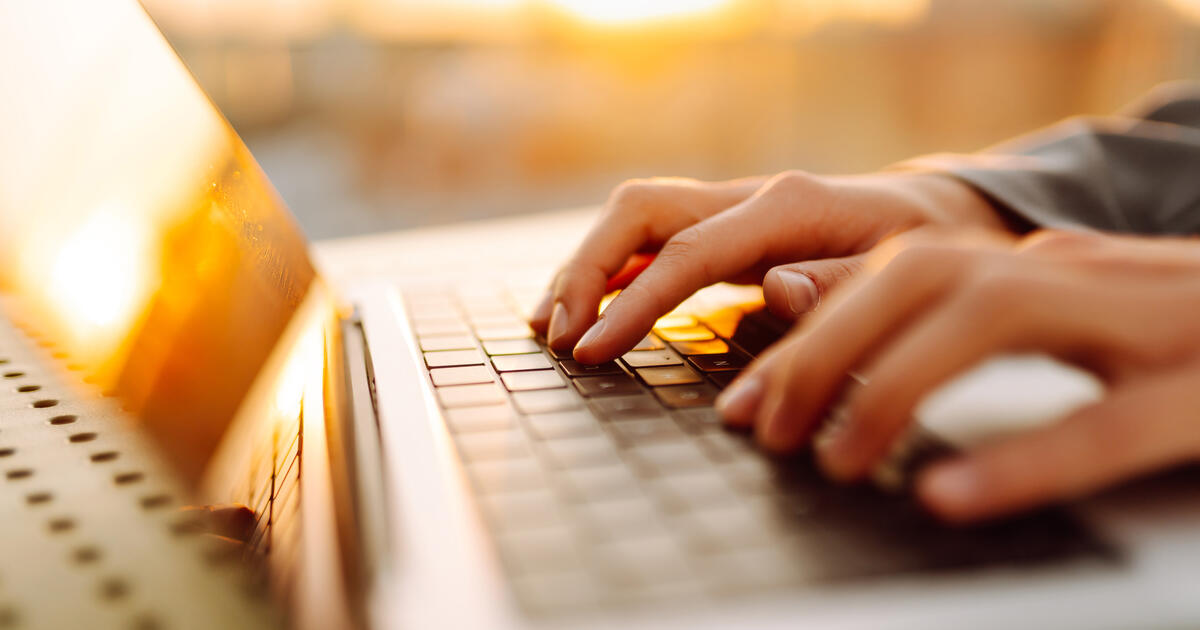Young female hands working on a laptop in the rays of the sunset-