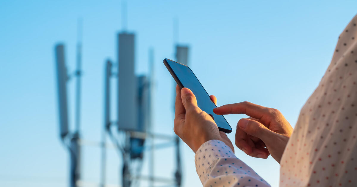 5G communications tower with man using mobile phone