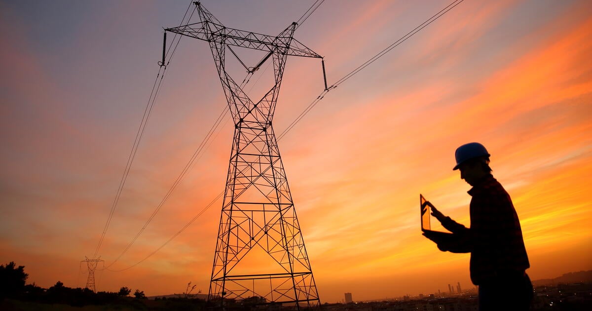 Engineer in silhouette underneath power lines