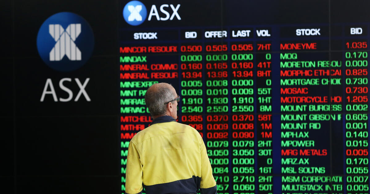 Person looking at an ASX stock market board displaying share prices and market data.