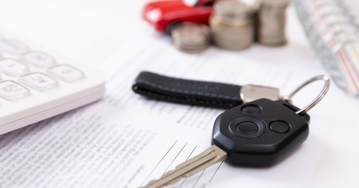 A car key fob resting on a desk next to a calculator