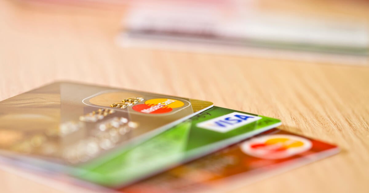 Credit and debit cards stacked on a wooden table, including Visa and Mastercard