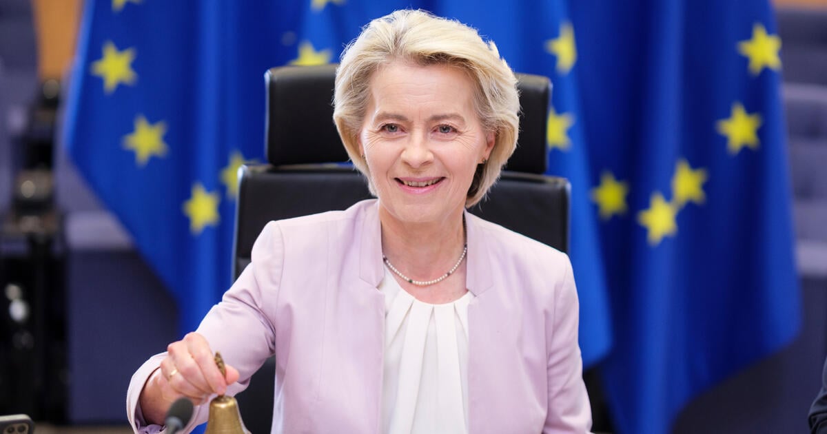 Ursula von der Leyen sitting before EU flags_Digital - SEOSocialEditorial image