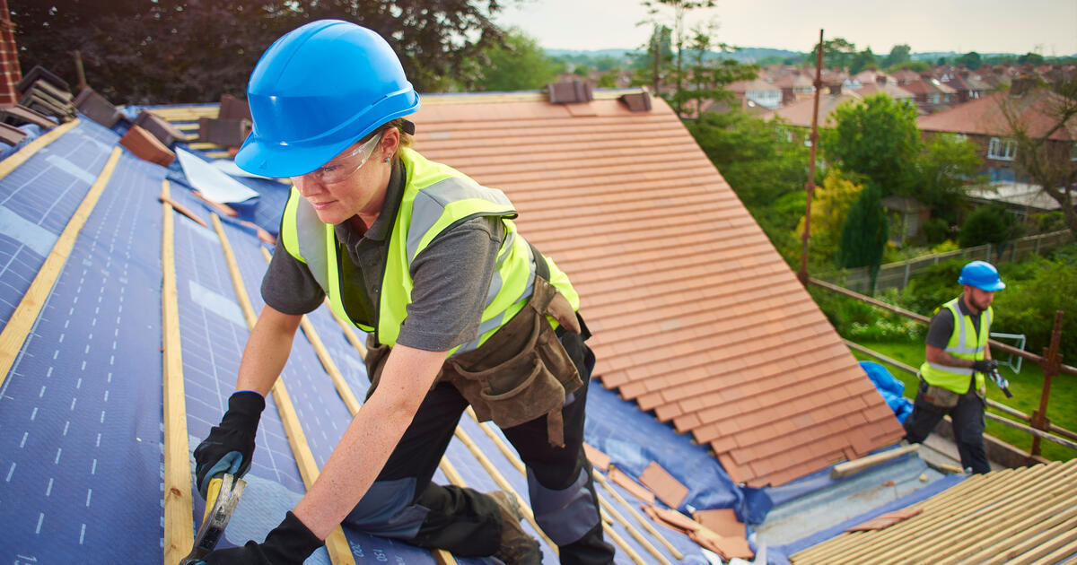 A female roofer fixing roof tiles