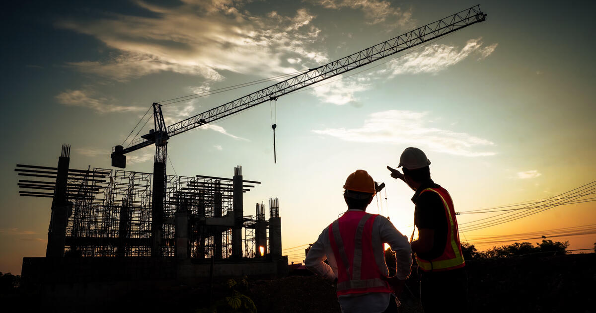 Silhouette of  a crane and workmen at a building site