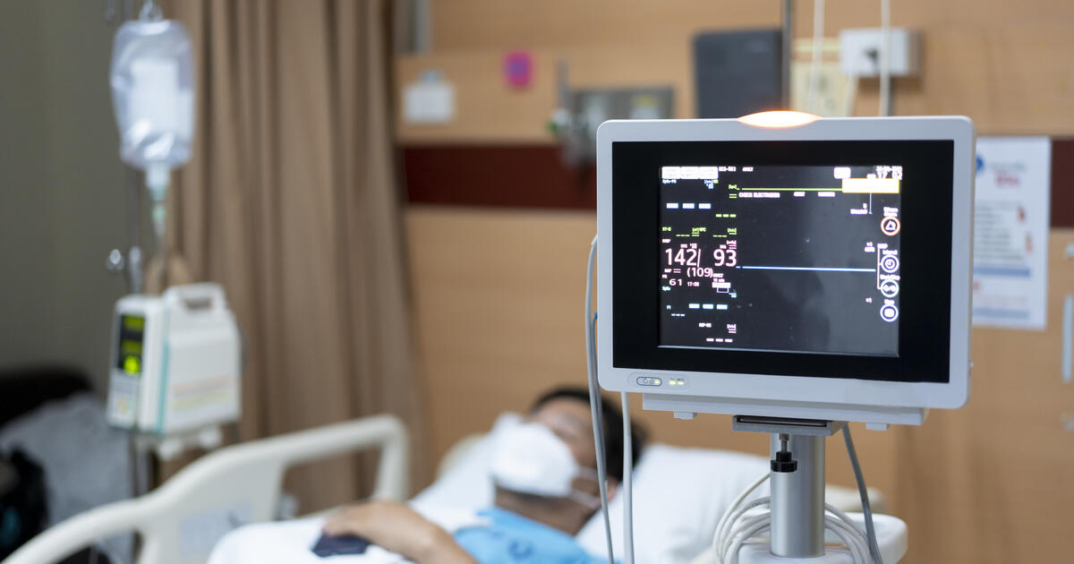 Hospital patient lying in bed with a vital signs monitor in the foreground