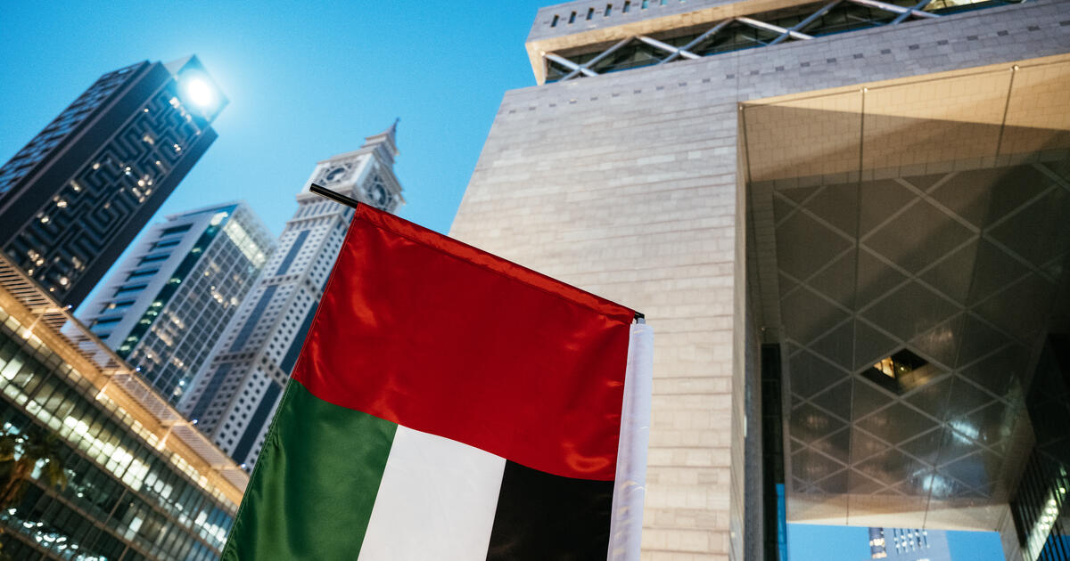 The Dubai International Financial Centre arch, with skyscrapers and the UAE flag