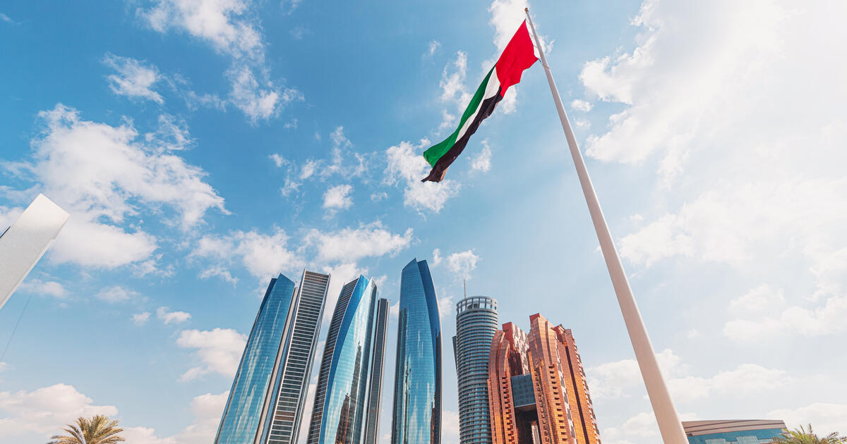 Low angle view of the UAE flag waving with modern skyscrapers on the background in Abu Dhabi 