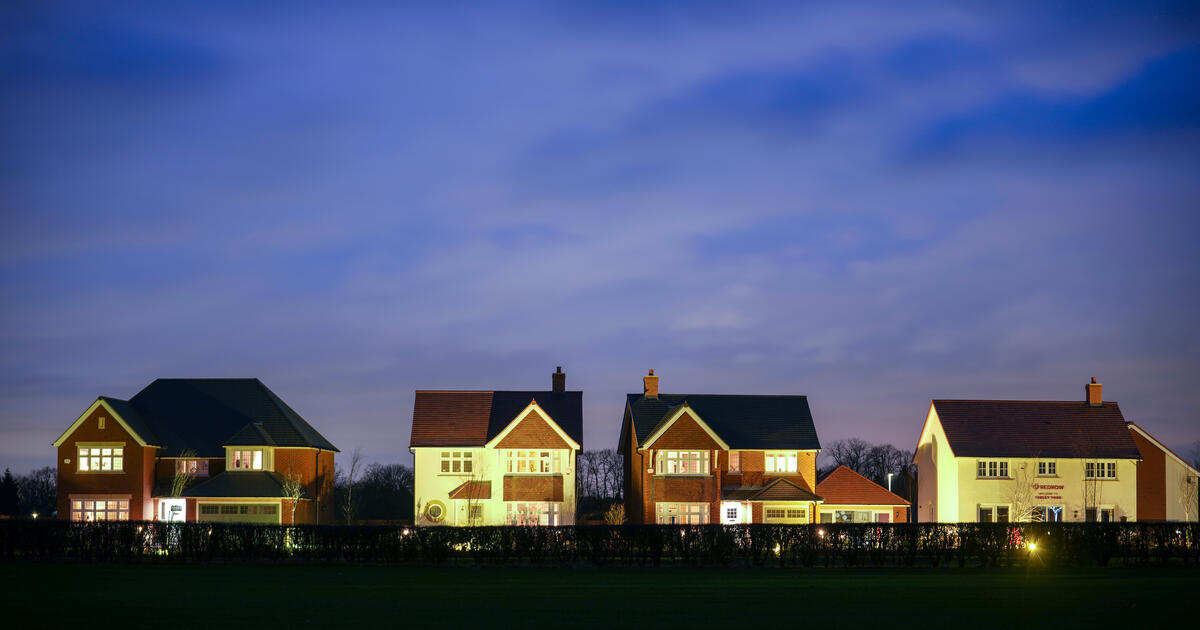 Row of modern detached houses lit up at dusk