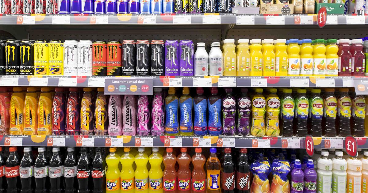 Rows of bottles of colourful fizzy drinks on display in a supermarket