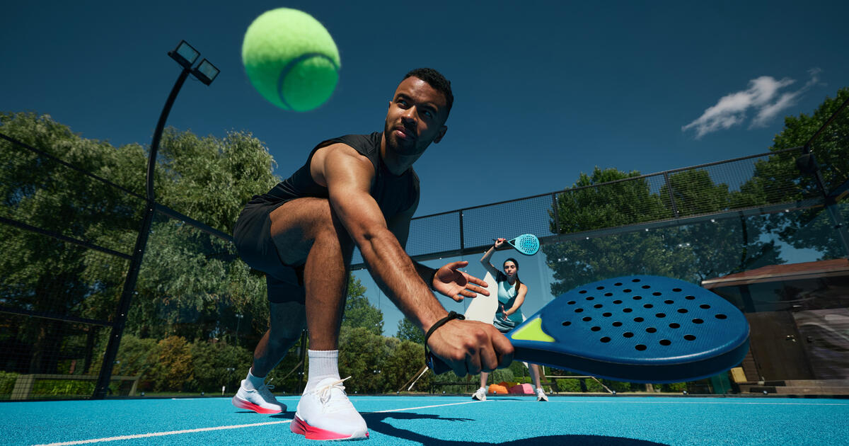 Padel player bends to play shot