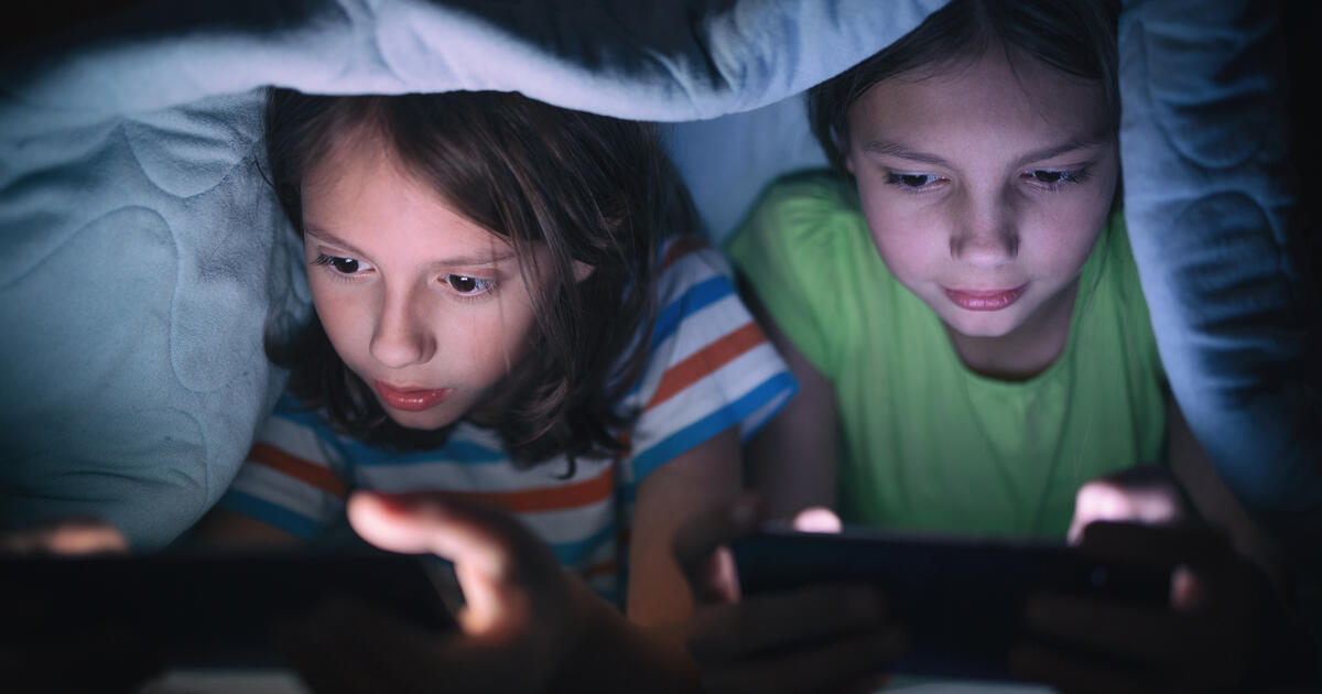 Boy and girl playing games on mobile phone_Digital - SEOSocialEditorial image