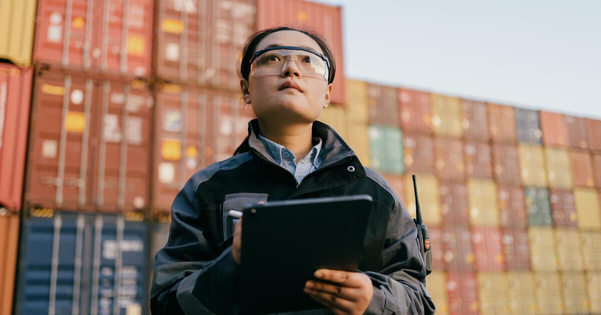 A supervisor checks shipping crates at a Chinese port