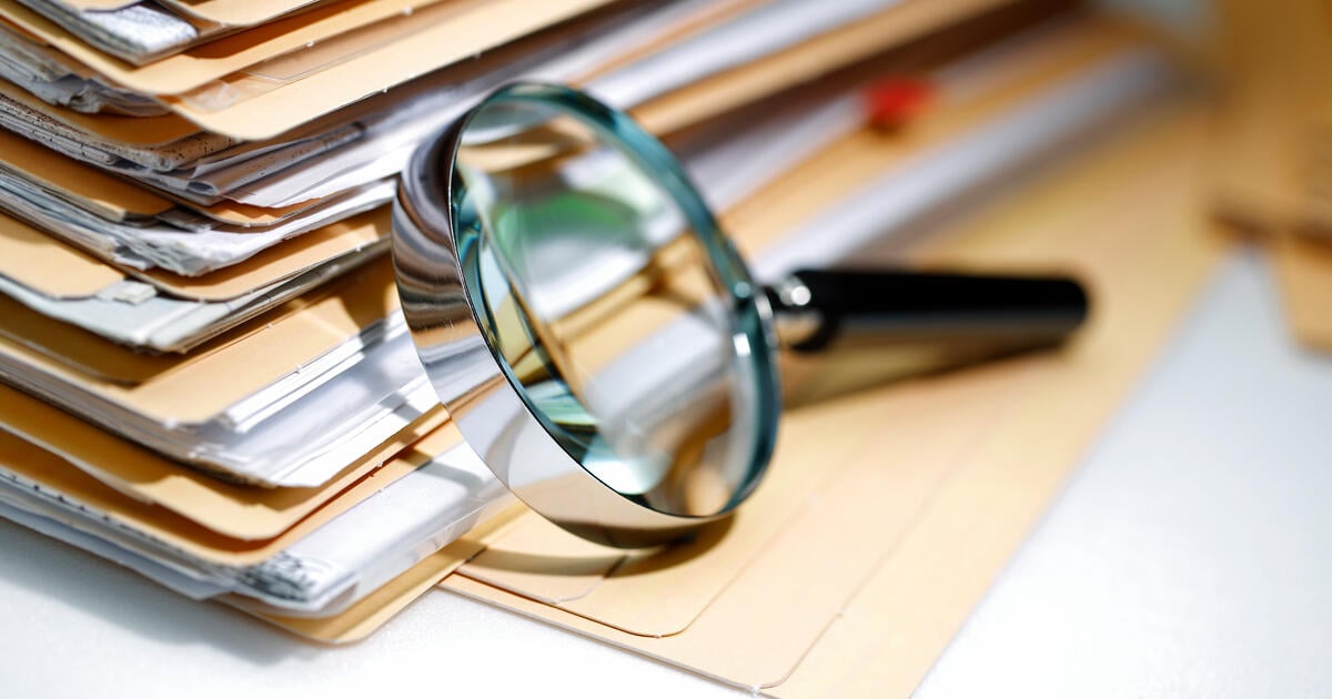 Documents pile and magnifying glass