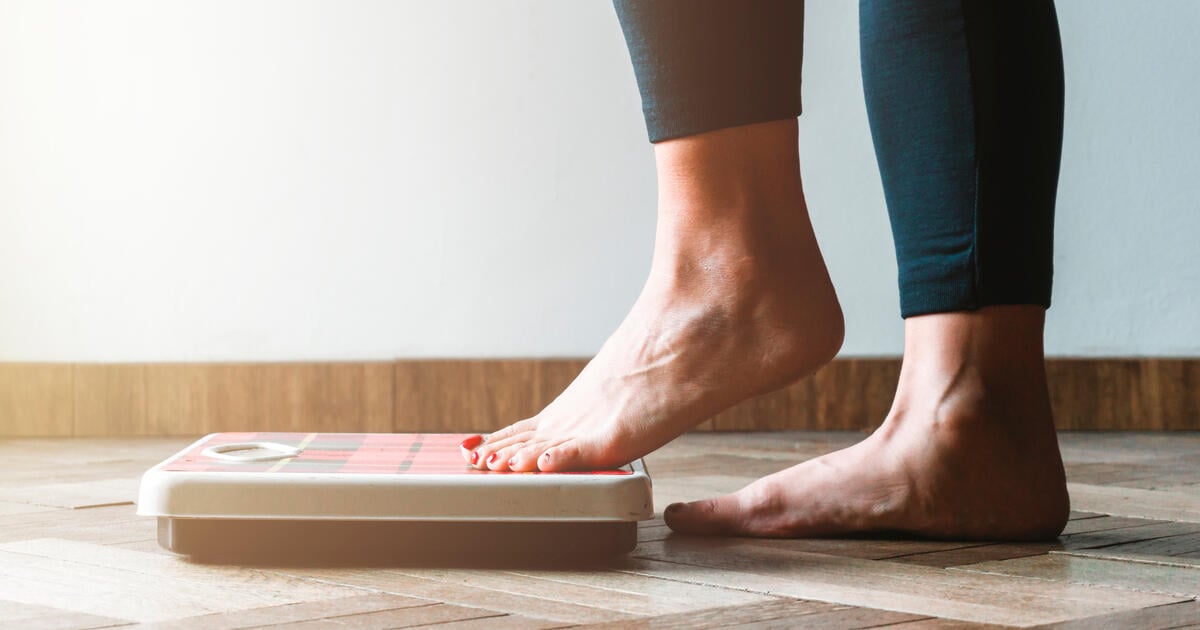 Female checking weight on scales_Digital - SEOSocialEditorial image