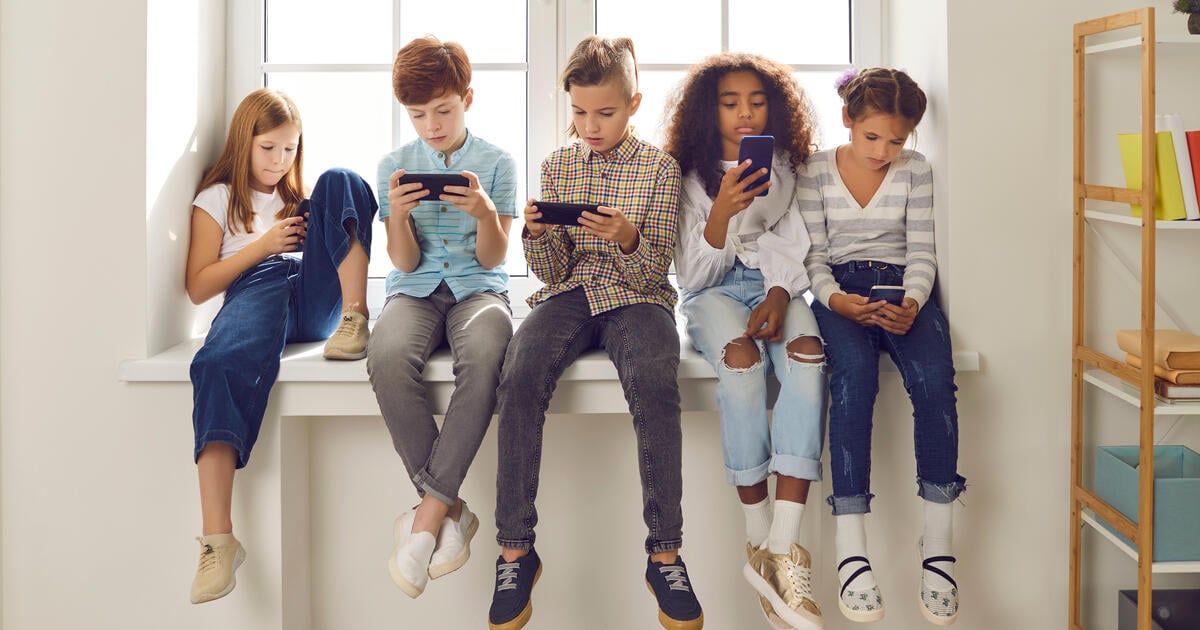 Five children sitting in a row using their mobiles_Digital - SEOSocialEditorial image