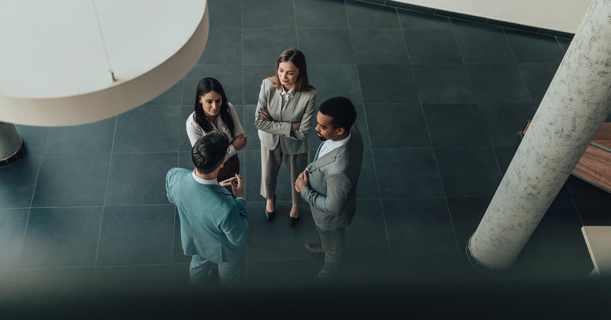 Diverse team of professionals gathers in a sleek, contemporary lobby, engaged in discussion